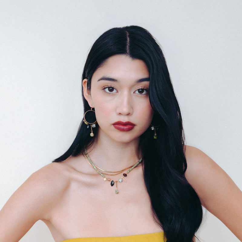 A woman with black hair modelling the Hailey Gerrits Austra Earrings and Necklace from the Fall Winter 2025 collection